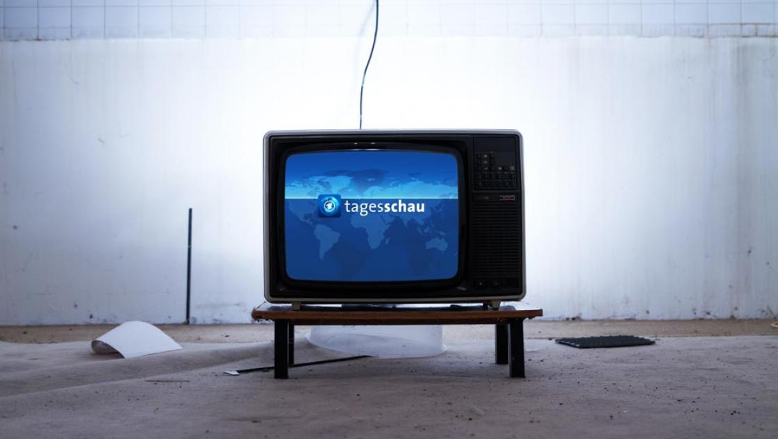 Mike Philippa (Unplash)|https://unsplash.com/@mikephilipp Ein Fernseher mit dem Bild der Tagesschau in einem kahlen Raum